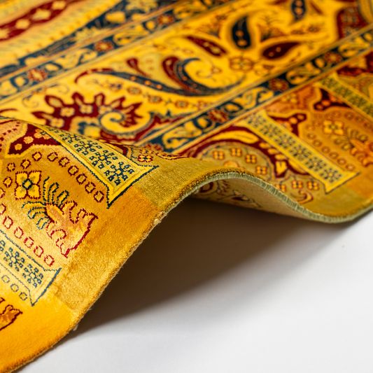 Golden silk rug with navy and red paisley floral detailing, handcrafted in a luxurious sheen finish with traditional Persian design elements.
