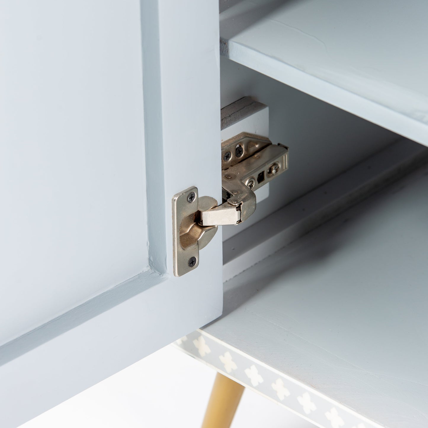 Grey bone inlay cabinet with floral vine pattern, brass legs, and carved bone knobs, handcrafted with spacious storage and artisanal charm.