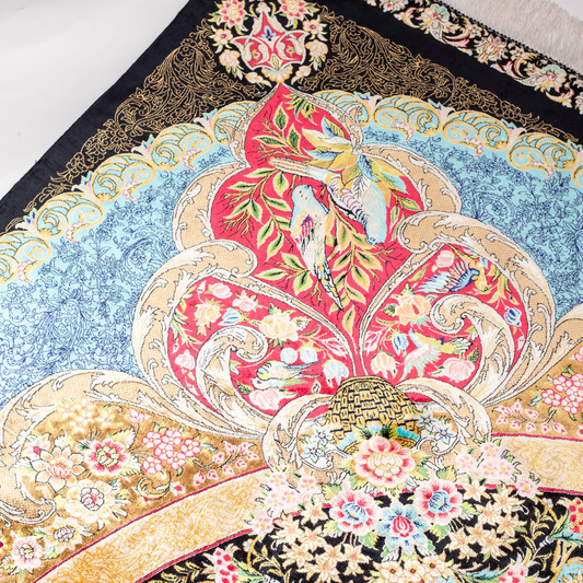 Luxury blue silk rug featuring a detailed central medallion, floral motifs, and ornate bird patterns in gold, coral, and black accents.