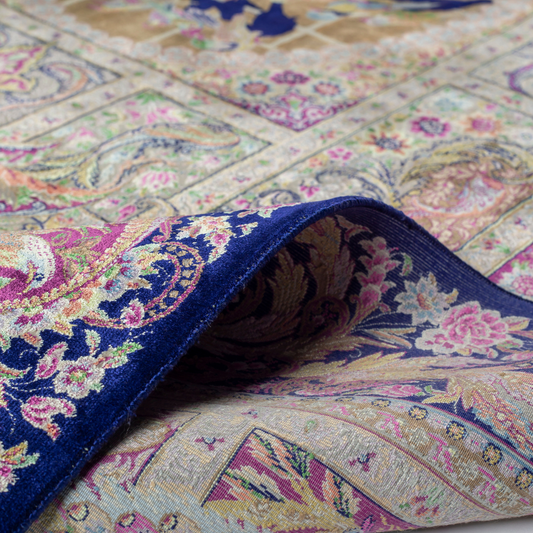 Luxurious silk rug with central bird tree, bordered by peacocks and florals. Handwoven in soft jewel tones with ornate framed details.