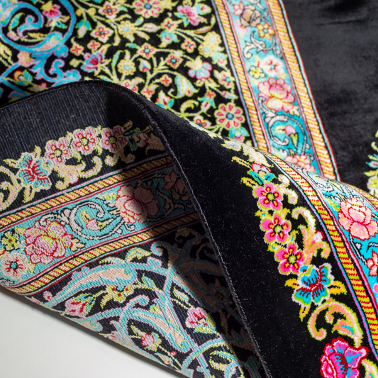 Luxurious silk rug featuring a central medallion in turquoise and pink, floral vases in corners, and ornate borders on a dark base.