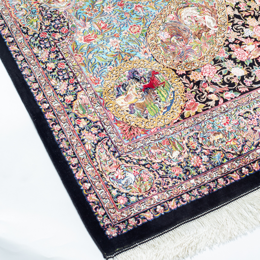 Close-up of the Veo Persian silk rug featuring a floral and bird pattern in navy, turquoise, and gold tones. 150x100 cm size.