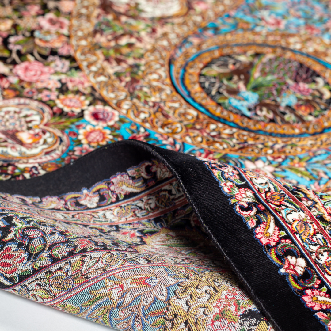 Close-up of the Veo Persian silk rug featuring a floral and bird pattern in navy, turquoise, and gold tones. 150x100 cm size.