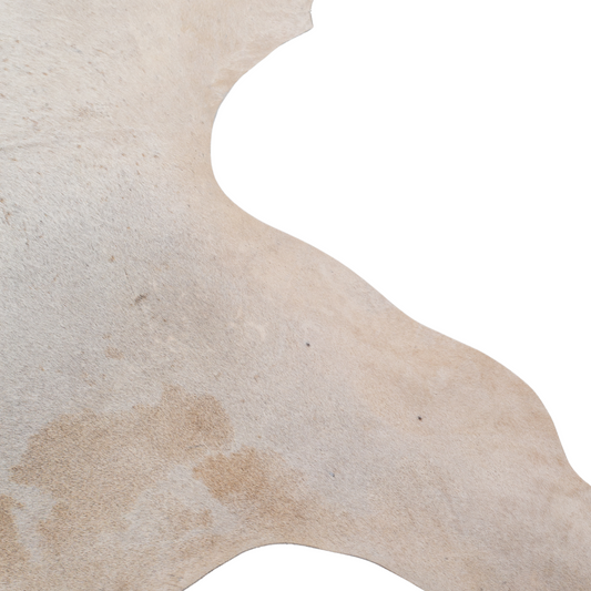 Natural cowhide rug with beige and chestnut brown markings, organic shape, and smooth textured finish.
