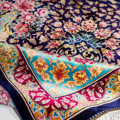 The Amore silk rug features an ornate floral medallion over a navy base, with vivid accents of turquoise, gold, and crimson in 350x250 cm.