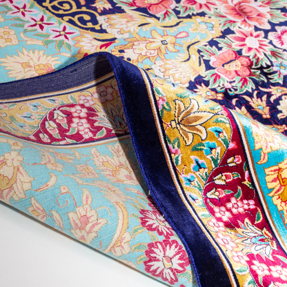 The Amore silk rug features an ornate floral medallion over a navy base, with vivid accents of turquoise, gold, and crimson in 350x250 cm.