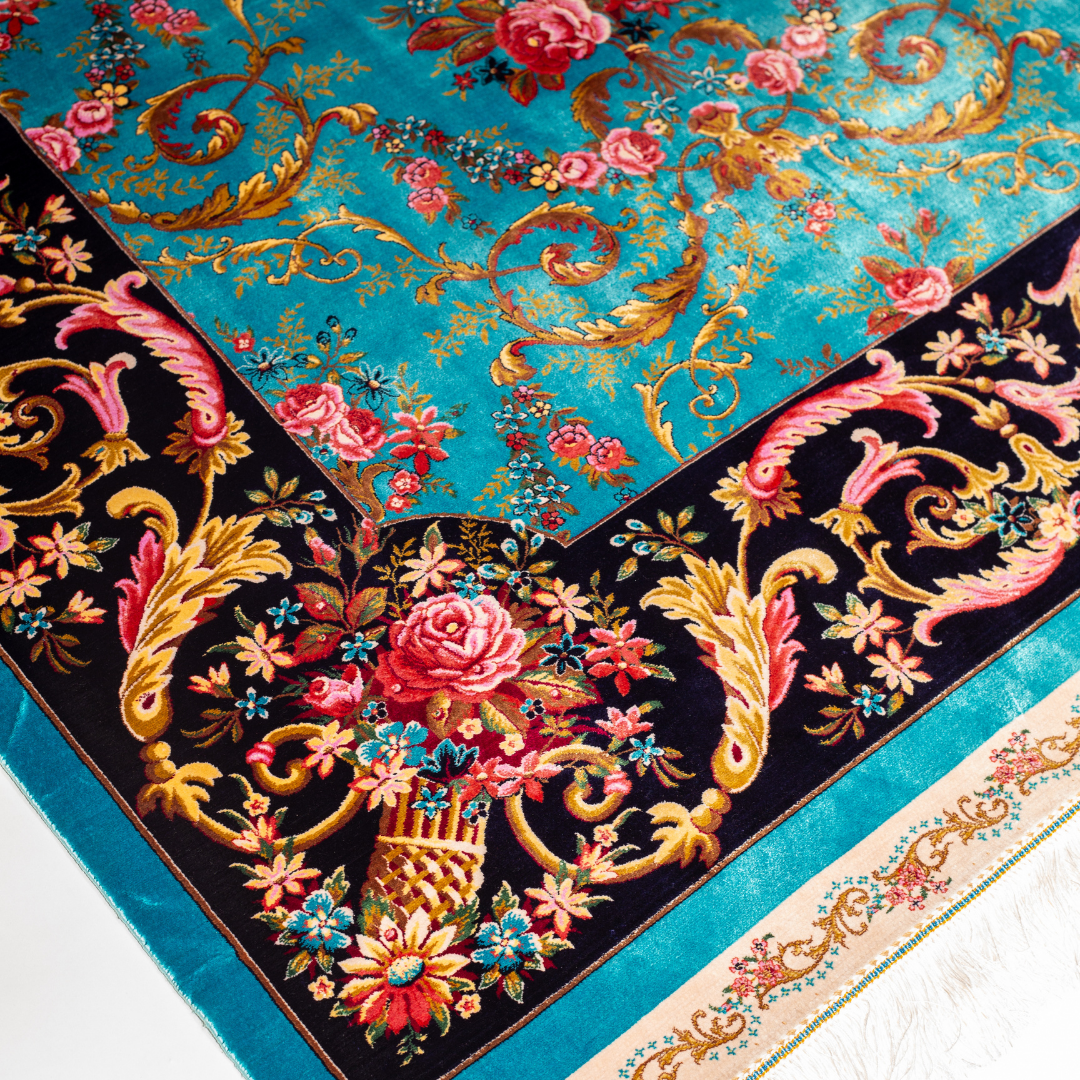 The Archie silk rug in turquoise with red floral motifs and golden scrolls, featuring a black ornamental border and exquisite handwoven detailing.