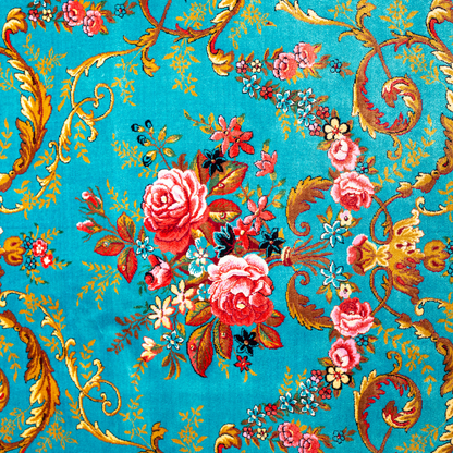 The Archie silk rug in turquoise with red floral motifs and golden scrolls, featuring a black ornamental border and exquisite handwoven detailing.
