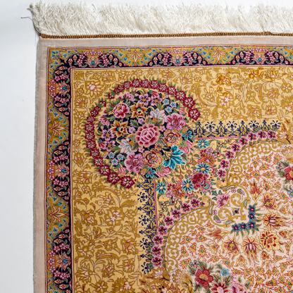 Handwoven silk rug in cream, gold, and blush tones featuring floral medallion, delicate vines, and ornate pastel detailing throughout.

