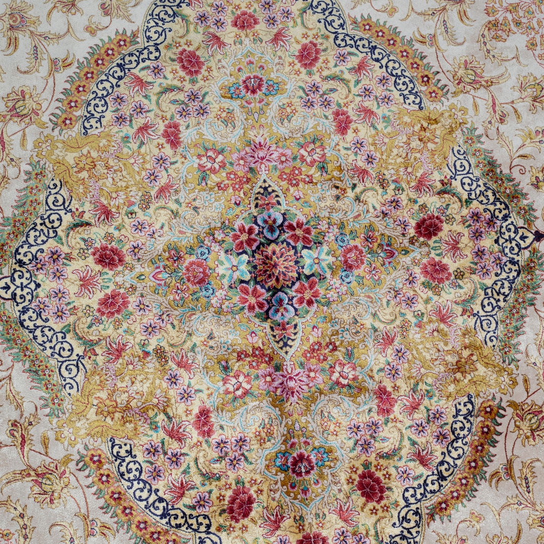 Handwoven silk rug in cream, gold, and blush tones featuring floral medallion, delicate vines, and ornate pastel detailing throughout.

