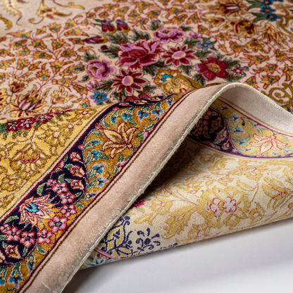 Handwoven silk rug in cream, gold, and blush tones featuring floral medallion, delicate vines, and ornate pastel detailing throughout.

