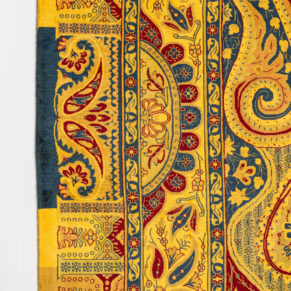 Golden silk rug with navy and red paisley floral detailing, handcrafted in a luxurious sheen finish with traditional Persian design elements.

