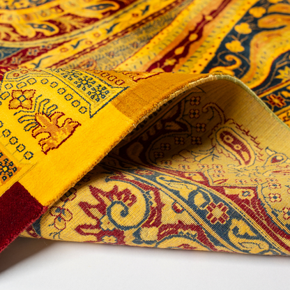 Golden silk rug with navy and red paisley floral detailing, handcrafted in a luxurious sheen finish with traditional Persian design elements.

