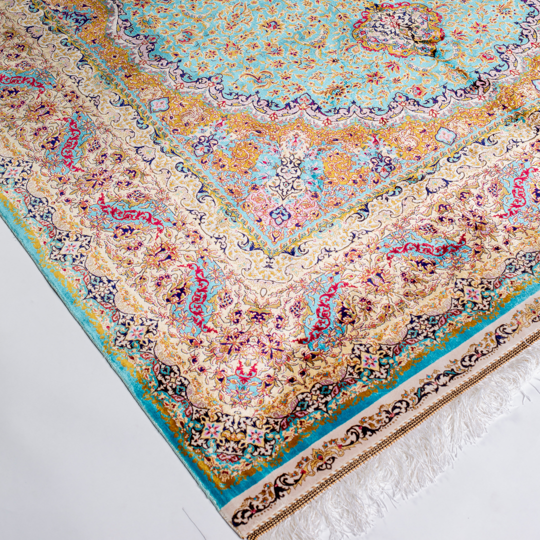 Intricately handwoven silk rug with medallion design, turquoise base, and ornate gold-maroon border for elegant interior styling.

