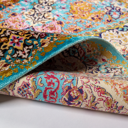 Intricately handwoven silk rug with medallion design, turquoise base, and ornate gold-maroon border for elegant interior styling.

