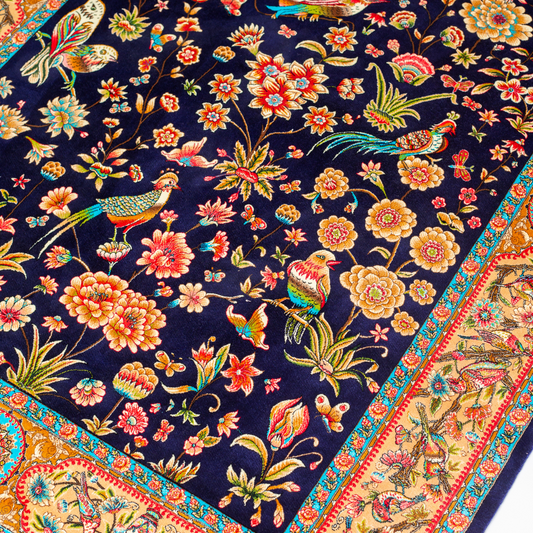 Eden silk rug featuring navy base with multi-colour florals and birds, hand-finished with detailed borders.
