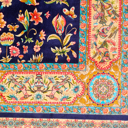 Eden silk rug featuring navy base with multi-colour florals and birds, hand-finished with detailed borders.
