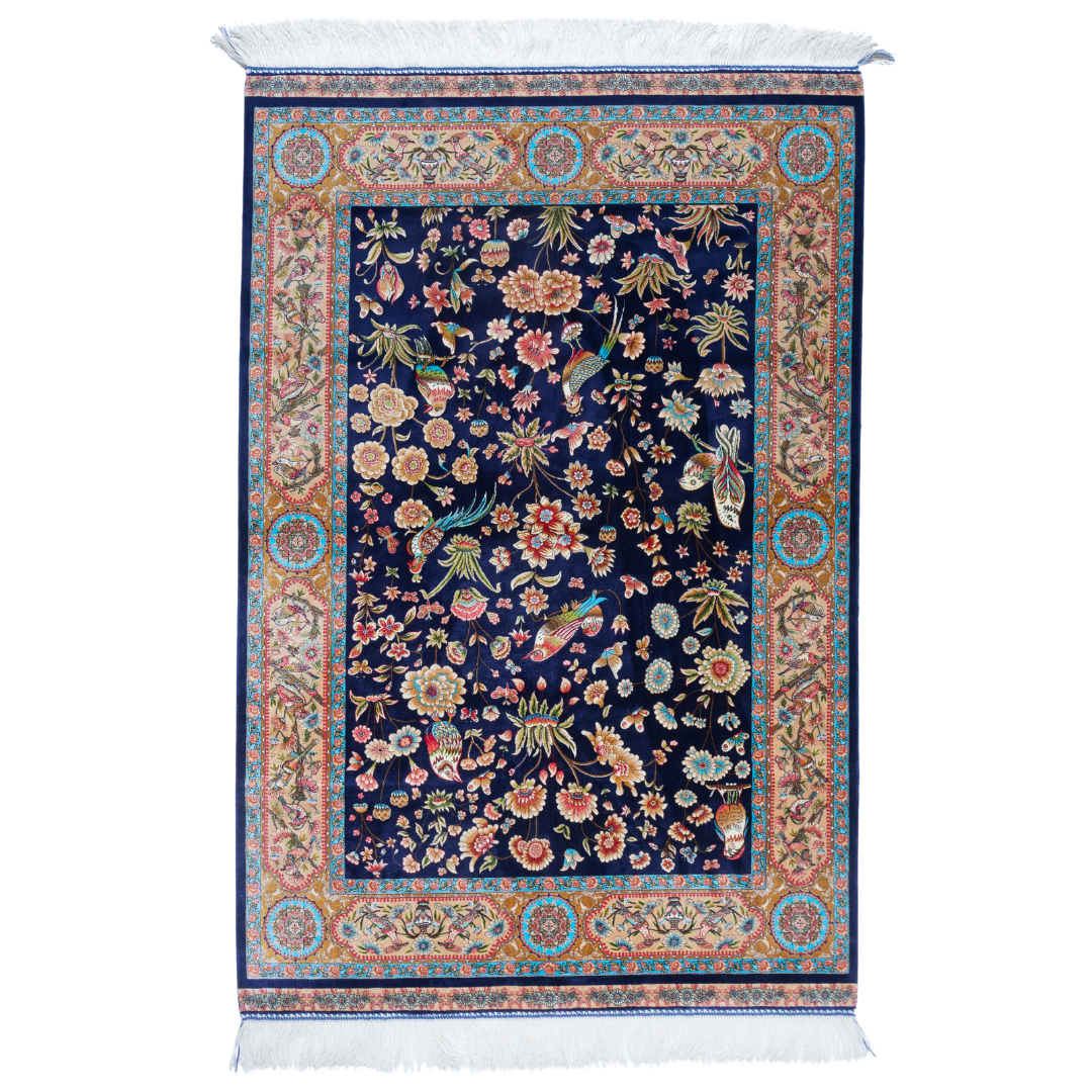 Eden silk rug featuring navy base with multi-colour florals and birds, hand-finished with detailed borders.

