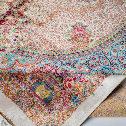 Silk Flow rug with a floral rosette medallion, ivory base, and ornate border in saffron, turquoise, plum, and blush tones.