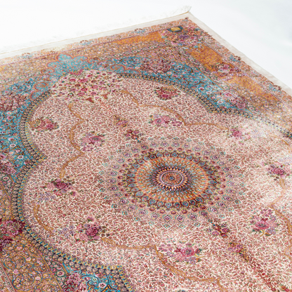 Silk Flow rug with a floral rosette medallion, ivory base, and ornate border in saffron, turquoise, plum, and blush tones.