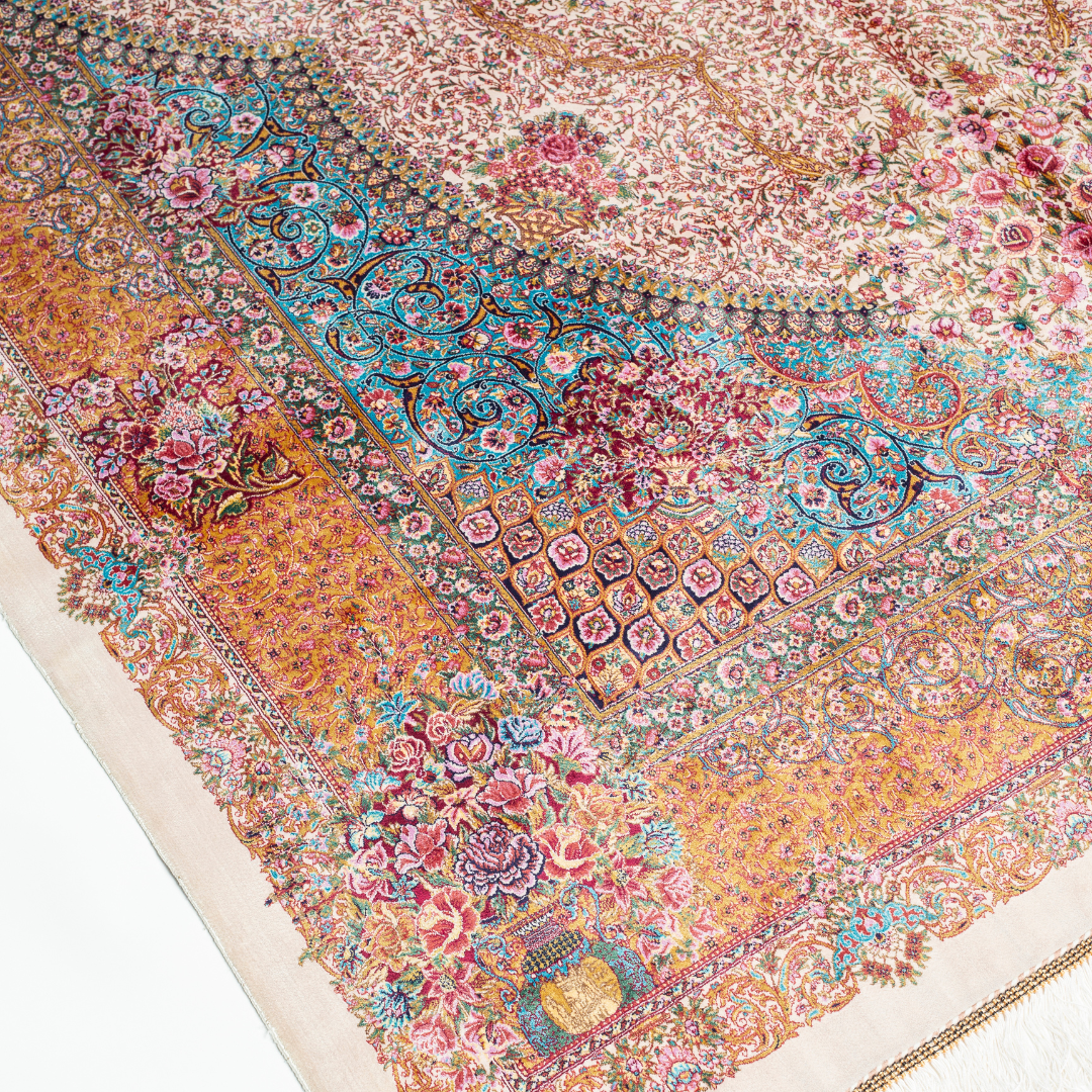 Silk Flow rug with a floral rosette medallion, ivory base, and ornate border in saffron, turquoise, plum, and blush tones.