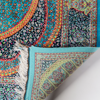 Jaze Silk Rug featuring a central floral medallion on a turquoise base with red, green, and black detailing, size 150x100 cm.