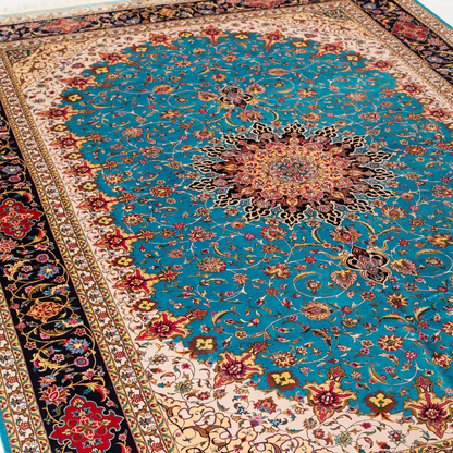 Intricately designed silk rug with turquoise base, floral patterns, and central medallion in red and gold – hand-finished and richly detailed.