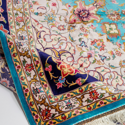 Intricately designed silk rug with turquoise base, floral patterns, and central medallion in red and gold – hand-finished and richly detailed.