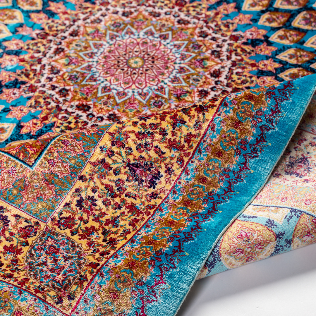 Maki silk rug featuring a turquoise blue base with intricate gold, ruby red, ivory, and fuchsia floral medallion design in a symmetrical pattern.

