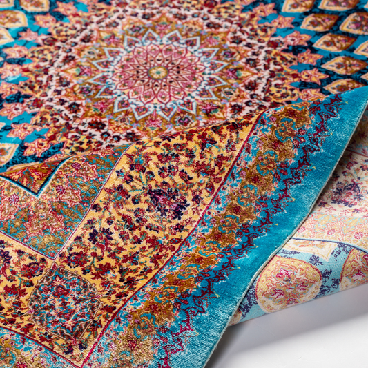Maki silk rug featuring a turquoise blue base with intricate gold, ruby red, ivory, and fuchsia floral medallion design in a symmetrical pattern.

