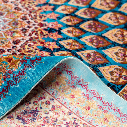 Maki silk rug featuring a turquoise blue base with intricate gold, ruby red, ivory, and fuchsia floral medallion design in a symmetrical pattern.
