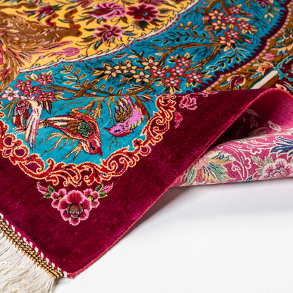 Opulent silk rug with ruby base and turquoise floral accents. Detailed handwoven artistry ideal for luxury, dramatic interior settings.

