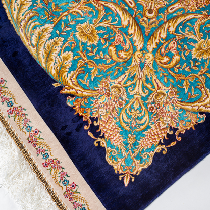 Elegant silk rug with flying birds and floral tree scene, bordered in ornate gold and blue. Handwoven with incredible detail and texture.

