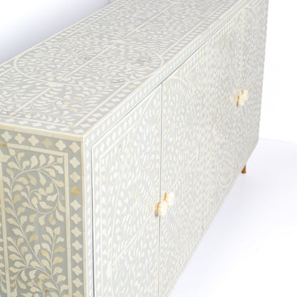 Grey bone inlay cabinet with floral vine pattern, brass legs, and carved bone knobs, handcrafted with spacious storage and artisanal charm.