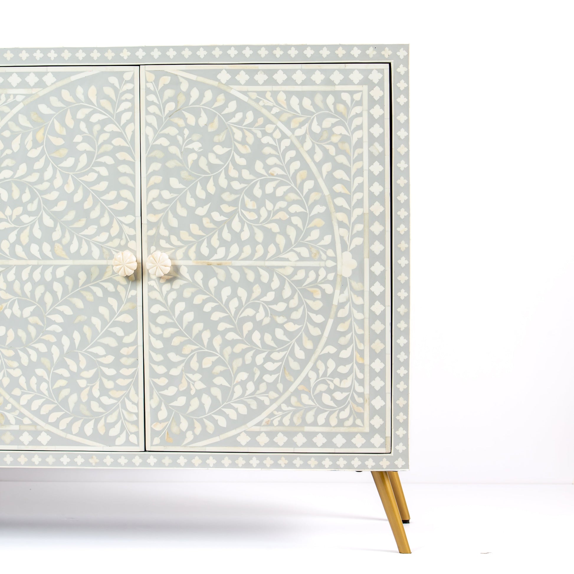 Grey bone inlay cabinet with floral vine pattern, brass legs, and carved bone knobs, handcrafted with spacious storage and artisanal charm.