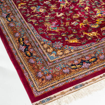 Silk rug in deep garnet red with majestic horsemen, animals, and ornate border work. Handwoven art that brings dynamic motion to interiors.

