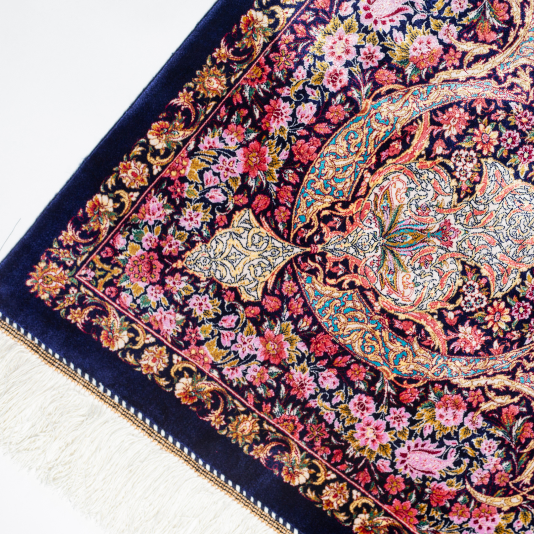 Elegant silk rug in navy, pink, gold, and turquoise with detailed-inspired floral and dancer motifs.


