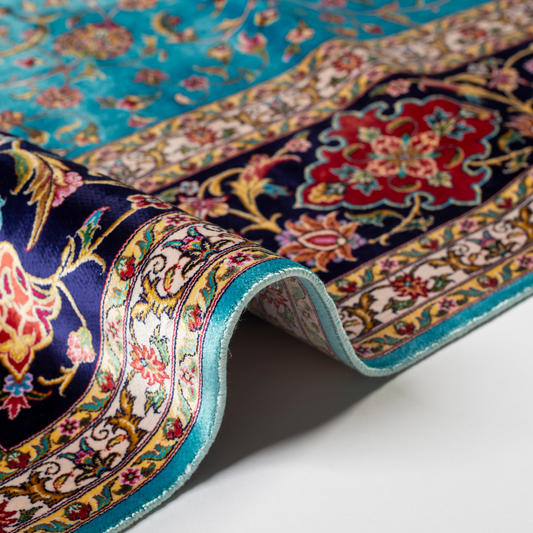 Aquamarine silk rug with coral and ivory floral motifs, framed by an indigo border. Handwoven with intricate detail and radiant sheen.

