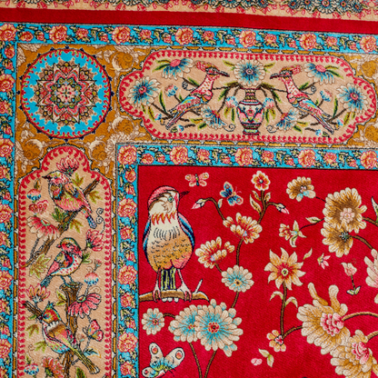 Crimson red silk rug featuring multi-colour floral and bird motifs, accented with turquoise, ivory, and gold detailing.