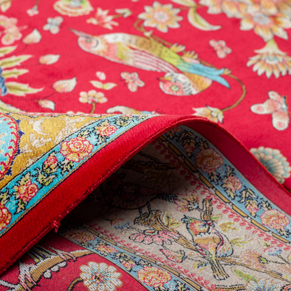 Crimson red silk rug featuring multi-colour floral and bird motifs, accented with turquoise, ivory, and gold detailing.