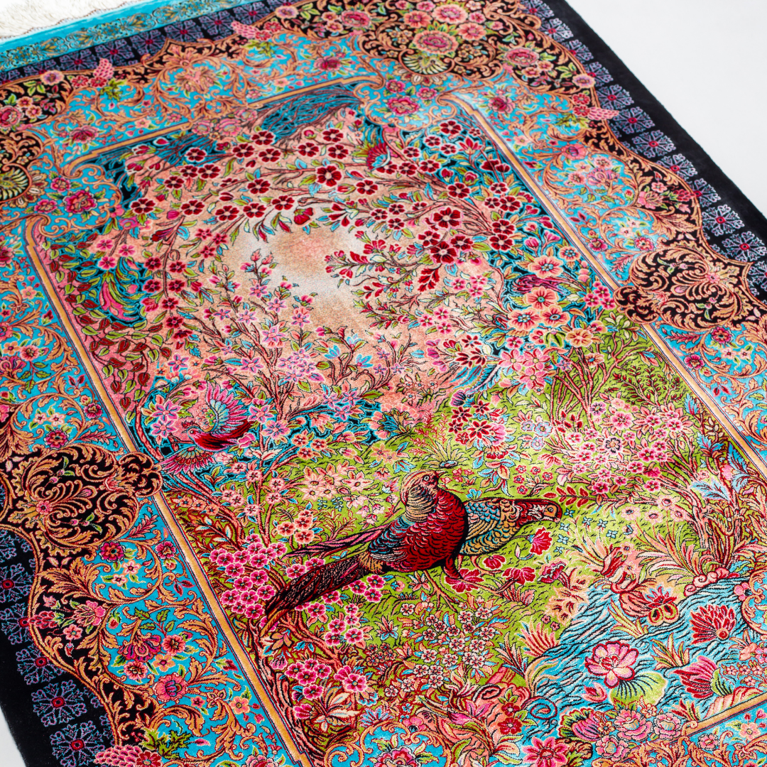 Tapin Silk Rug featuring nature-inspired artwork with birds, flowers, and flowing water on an ivory base with turquoise and black borders, 150x100 cm.