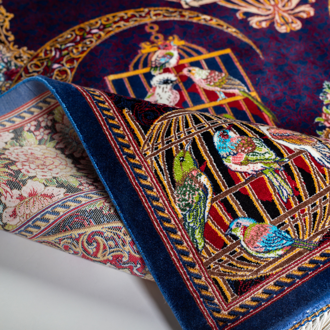Terra silk rug with navy base, multi-colour birdcage motifs, floral accents, and detailed animal and garden scenes in 150x100 cm size.
