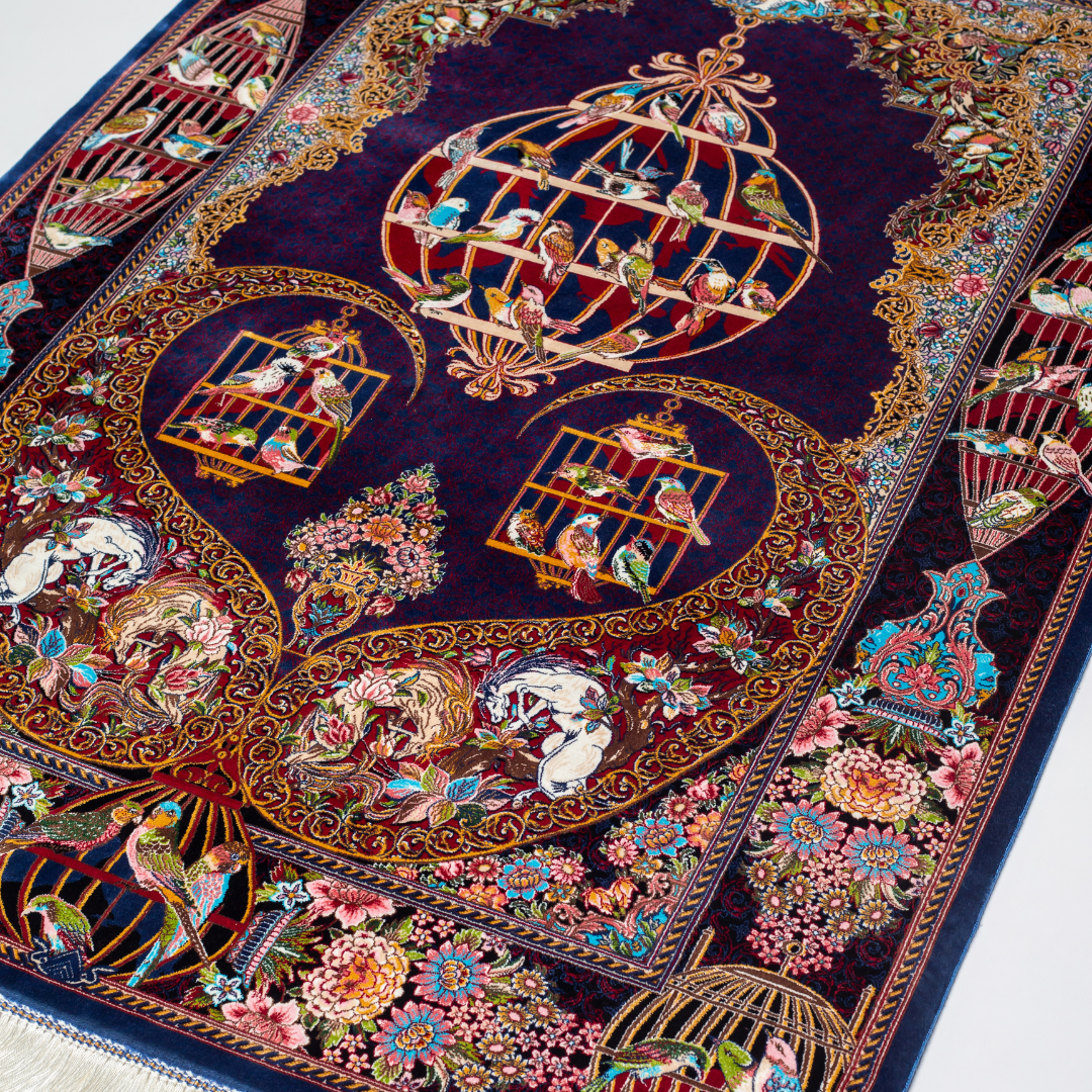 Terra silk rug with navy base, multi-colour birdcage motifs, floral accents, and detailed animal and garden scenes in 150x100 cm size.
