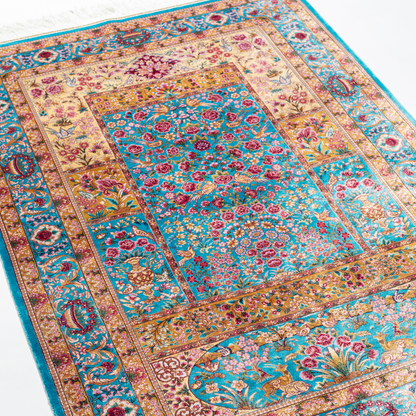 Tolly Silk Rug featuring ruby red floral and bird motifs on an aqua-blue base with golden ornate panels, size 150x100 cm.