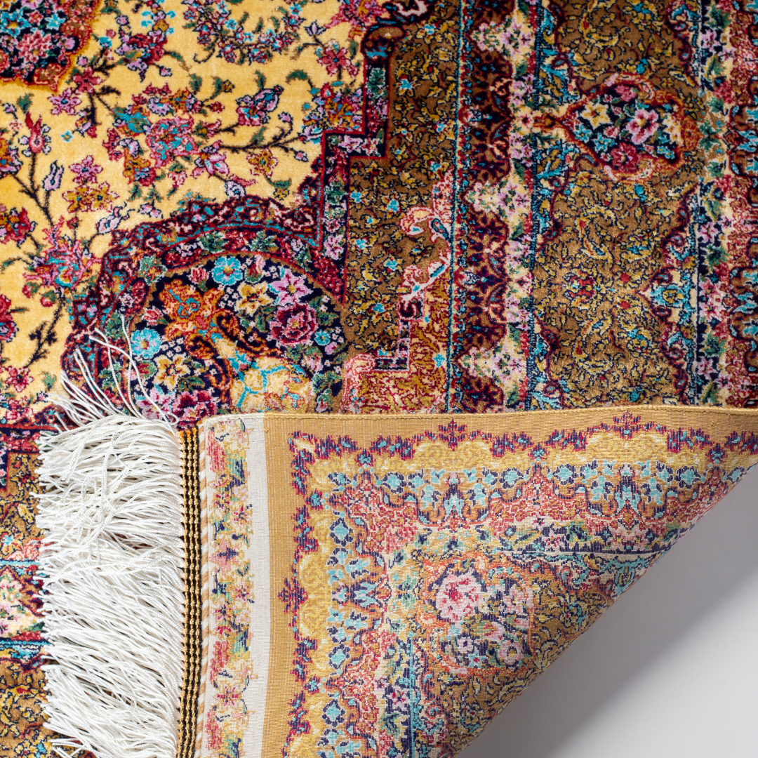 Golden silk rug with floral medallion center and wine-toned border, featuring intricate handmade detailing and vibrant color accents.
