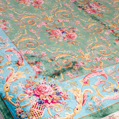 Green silk rug with detailed rose motifs and a turquoise border, featuring Persian-inspired floral designs and ornamental flourishes.