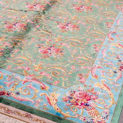 Green silk rug with detailed rose motifs and a turquoise border, featuring Persian-inspired floral designs and ornamental flourishes.
