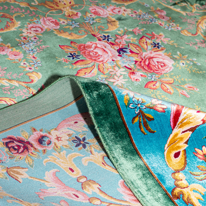 Green silk rug with detailed rose motifs and a turquoise border, featuring Persian-inspired floral designs and ornamental flourishes.