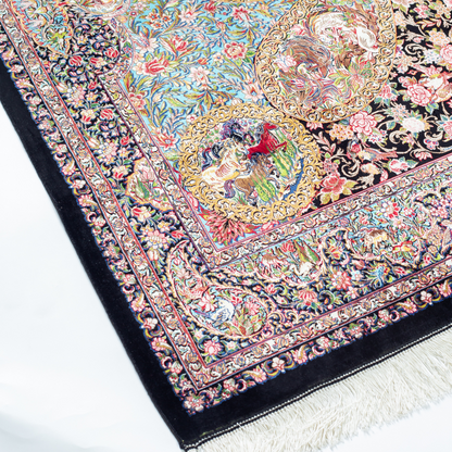 Close-up of the Veo Persian silk rug featuring a floral and bird pattern in navy, turquoise, and gold tones. 150x100 cm size.
