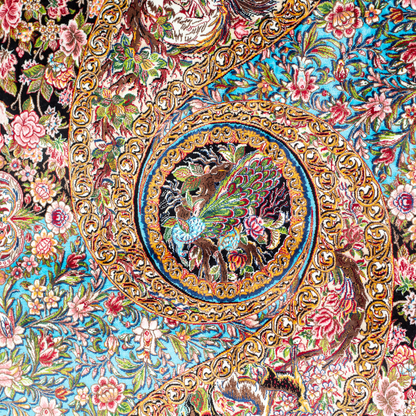 Close-up of the Veo Persian silk rug featuring a floral and bird pattern in navy, turquoise, and gold tones. 150x100 cm size.
